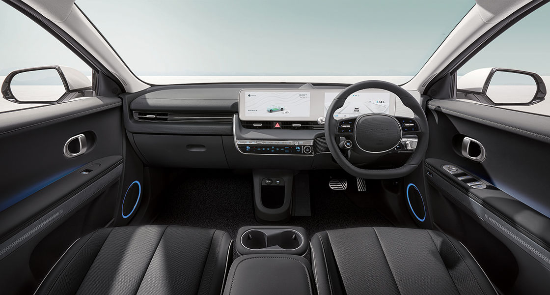 Interior Hyundai Ioniq 5 menampilkan desain modern dengan layar lebar, jok kulit hitam, dan detail-detail elegan, termasuk setir kompak dan pencahayaan ambient.