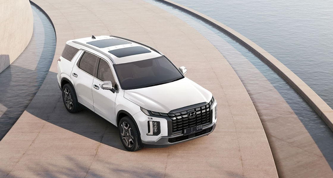 Hyundai Palisade berwarna putih yang memiliki desain modern dengan grille yang mencolok dan logo Hyundai di bagian depan